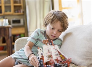 Caucasian boy sitting on sofa playing with toy boat