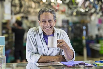 Portrait of smiling Caucasian man drinking coffee in bicycle shop