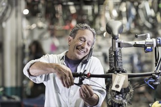 Caucasian man talking on telephone and repairing brakes on bicycle