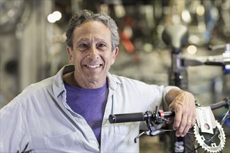 Portrait of smiling Caucasian man leaning on bicycle in shop