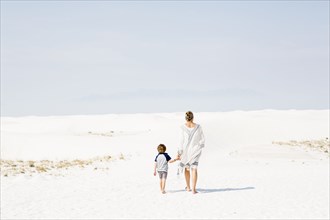 Caucasian mother and son walking in sand
