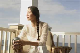 Woman having a cup of coffee on the porch