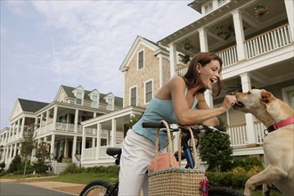 Young woman on a bike giving her dog a treat