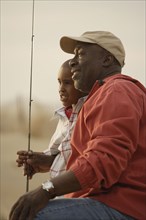 African father and son on beach with fishing gear