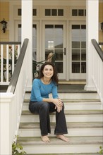 Hispanic woman sitting on porch stairs smiling