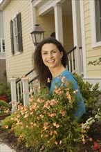 Hispanic woman smiling with plants in front of house