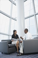 Businessman and businesswoman talking in office lobby