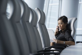 Asian businesswoman using cell phone in conference room