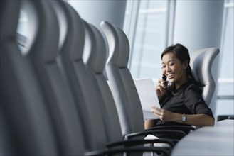 Asian businesswoman using cell phone in conference room
