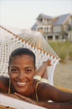 African woman laying in hammock at beach