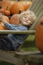 Boy in chair holding pumpkin