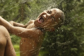 African American boy playing in sprinkler