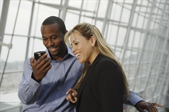 Multi-ethnic businesspeople looking at cell phone
