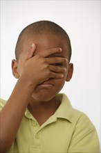 African American boy covering face with hand