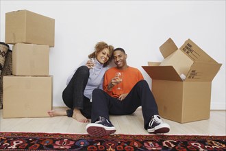 African couple with wine next to moving boxes