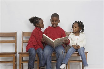 African boy reading to siblings