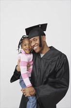 African male graduate holding daughter