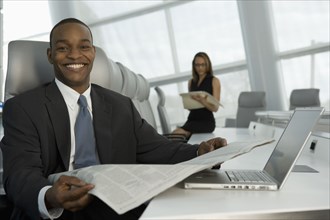 African businessman reading newspaper in conference room