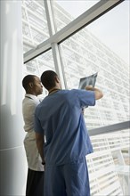 Multi-ethnic doctor and nurse reviewing x-ray by window