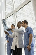 Multi-ethnic doctor and nurses reviewing x-ray by window