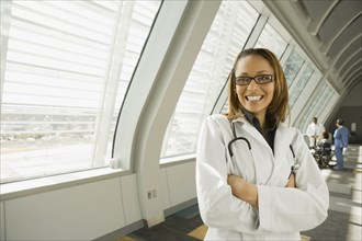 African doctor with arms crossed smiling in corridor
