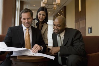 Multi-ethnic business people reviewing paperwork in lobby