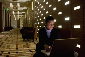 African businesswoman working on laptop late in lobby