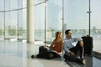 Multi-ethnic couple sitting in floor at airport