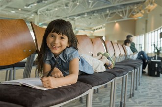Hispanic girl coloring in airport