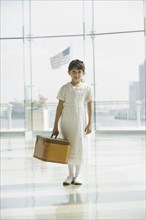 Hispanic girl with suitcase waiting in airport