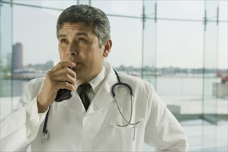 Hispanic doctor in lab coat speaking into dictaphone