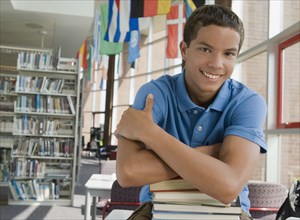 Mixed race teenager leaning on stack of books