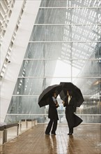 African businesswomen holding umbrellas in rain