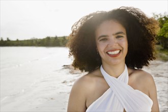 Hispanic woman smiling near ocean