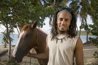 Hispanic man leading horse near beach