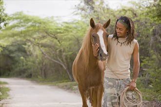 Hispanic man leading horse down dirt road