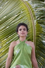 Hispanic woman in sarong near palm leaf