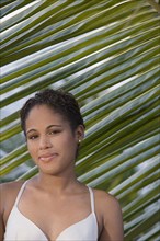 Hispanic woman standing near palm leaf
