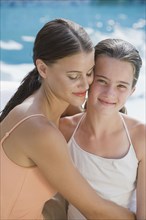 Mixed race woman and daughter in bathing suits hugging