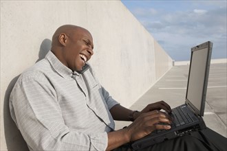 African businessman using laptop in parking lot