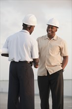 African businessmen in hard-hats shaking hands