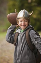 Mixed race boy in viking hat throwing a football