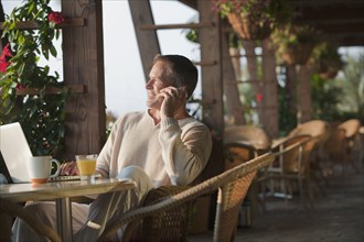Caucasian man talking on cell phone in restaurant