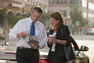 Caucasian business people looking at newspaper