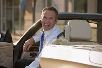 Caucasian businessman smiling in convertible