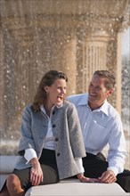 Caucasian couple laughing near spraying fountain