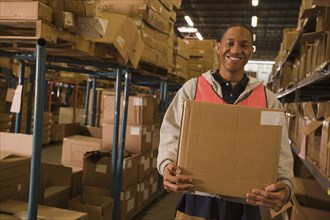 Black man carrying box in warehouse