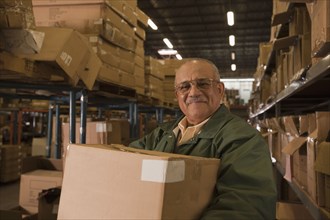 Mixed race man carrying box in warehouse