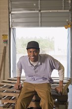 Black man sitting on pallets in warehouse