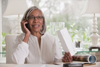 Black woman holding paper talking on cell phone